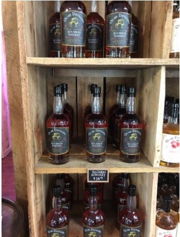 Bottles of Ozark Missouri Bourbon Whiskey lined up on a wooden shelf.