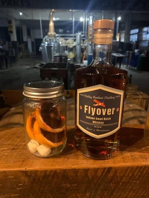 A bottle of Flyover Aviator Indiana Small Batch Whiskey with an old-fashioned blood orange mason jar kit on the left.