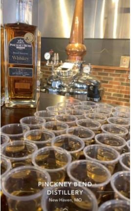 A bottle of Pinckney Bend Distillery’s Rested American Whiskey behind a group of whiskey glasses on a table.