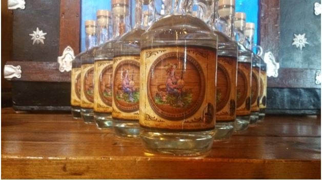 Bottles of Howlin' Hounds Corn Whiskey placed on top of a wooden table.