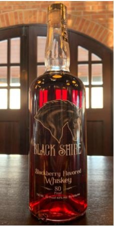 A bottle of Blackberry Whiskey on a wooden table inside the Black Shire Distillery.