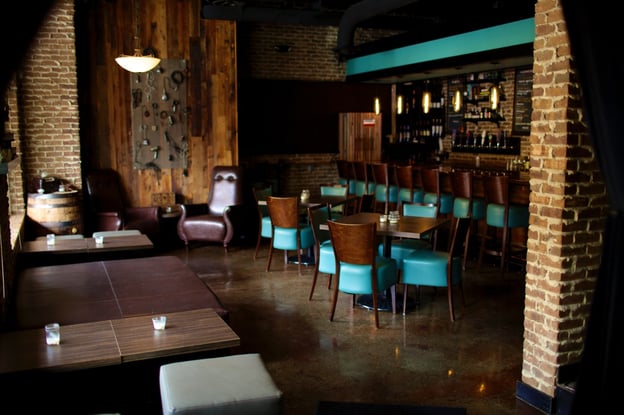 Well-lighted  bar and the wooden chairs are surrounded by brick walls and low lighting.