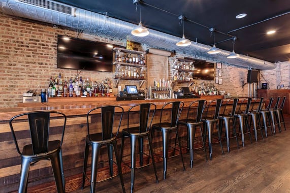  Image of a whiskey bar with black high chairs aligned at the counter