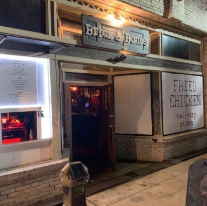 Facade of Brick & Bones with the signage hung above the entrance and another that reads Fried Chicken delivery pickup.