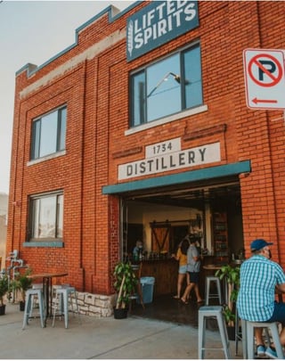 An image of Lifted Spirits Distillery’s facade with people enjoying the spirits and going to the counter.