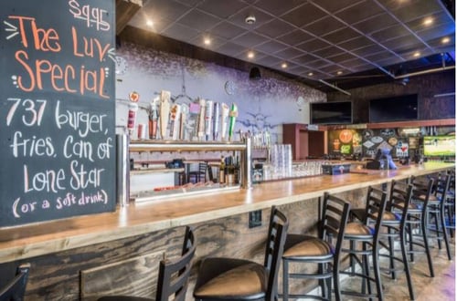 Brightly lit counter with empty chairs in front and small blackboard 