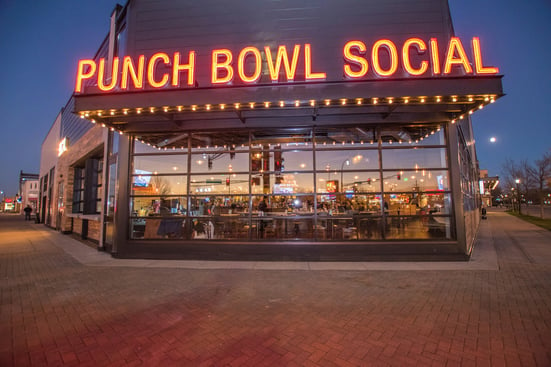 Punch Bowl Social’s front-facing side of the building with the lights turned on.