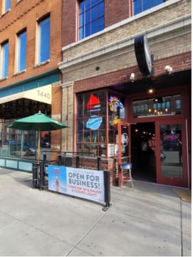 Society Sports and Spirits’ brick wall facade with signage “Open for business! Come on in & enjoy a Coors light!”