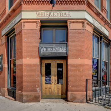 Whiskey Bar’s brick wall facade. The signage above has the name Whiskey Bar on it.