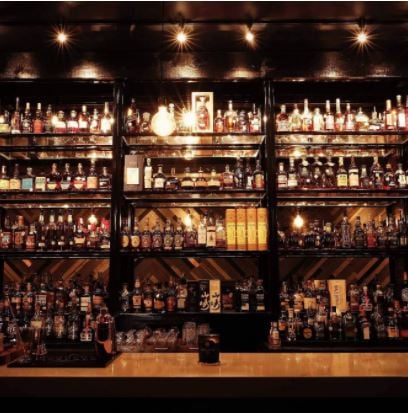 Whiskey bar at Whiskeys. It is dimly lit and shows the black shelves filled with spirits